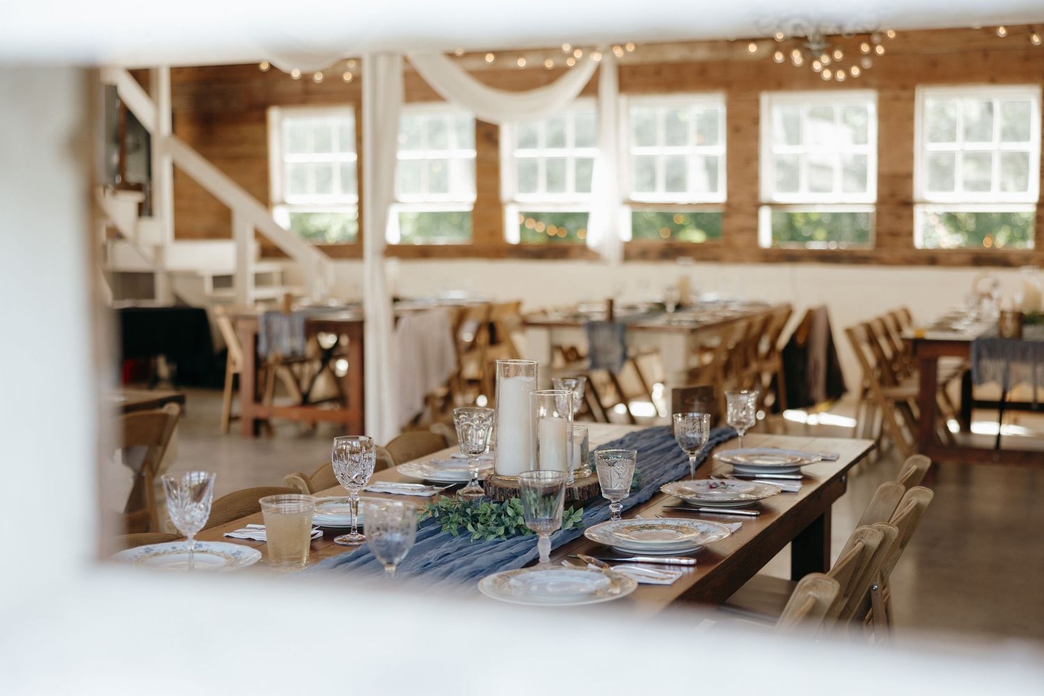 Bright and airy pottery studio interior with workstations, string lights, and natural sunlight streaming through windows.