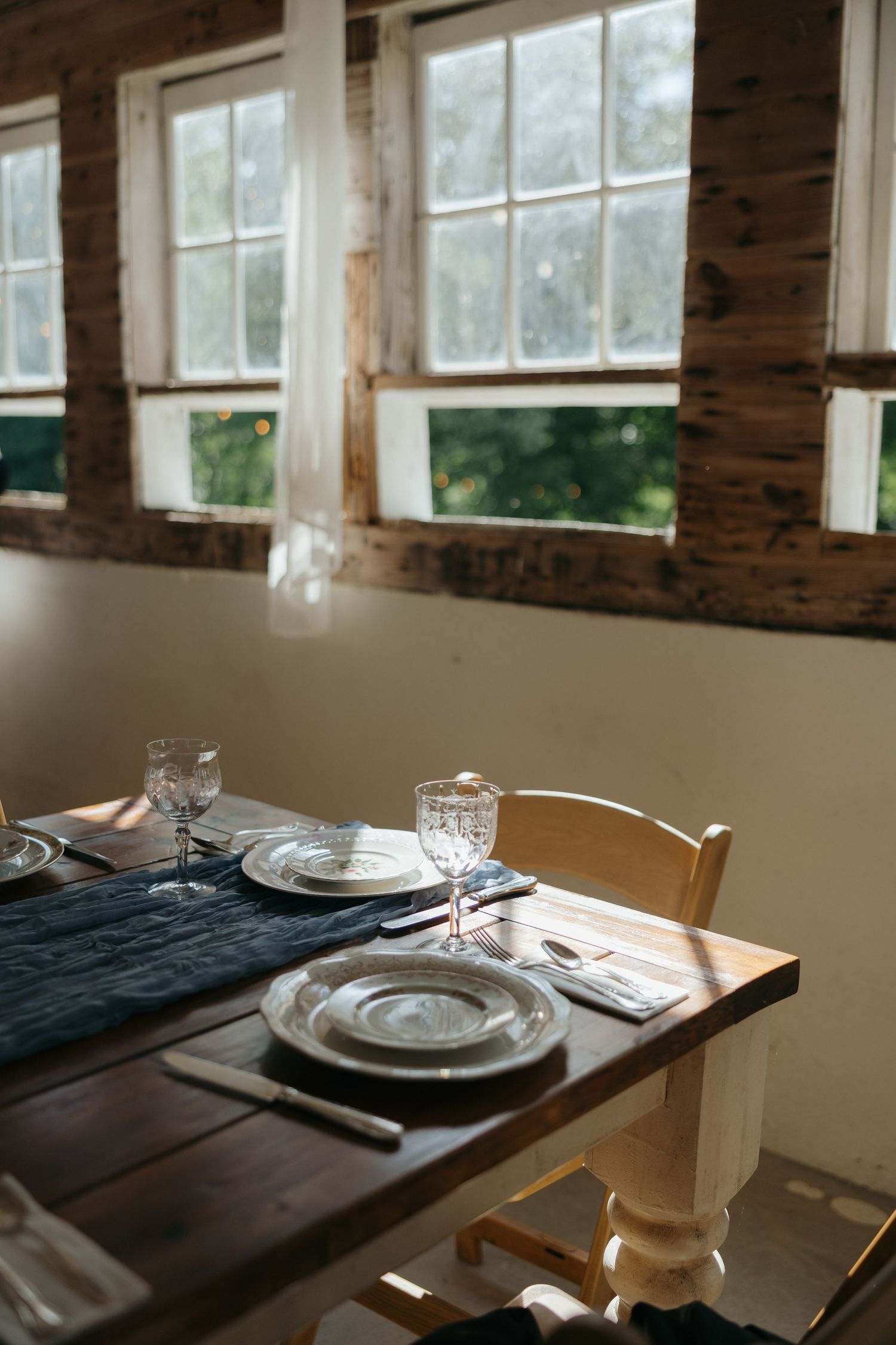 Elegant table settings in a rustic venue with brick walls and large windows letting in natural light.