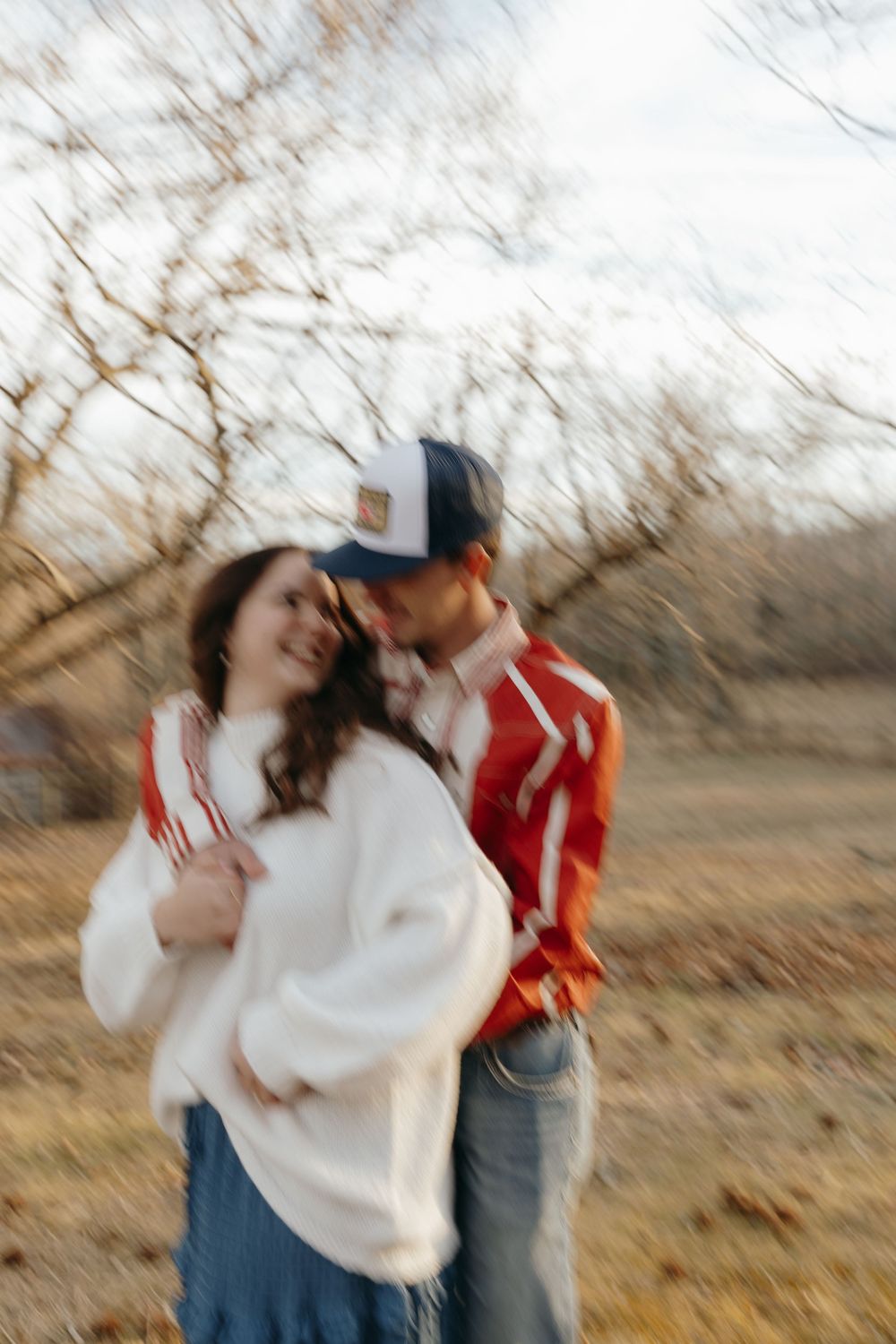 A romantic couple shares a tender moment outdoors in casual attire during golden hour.
