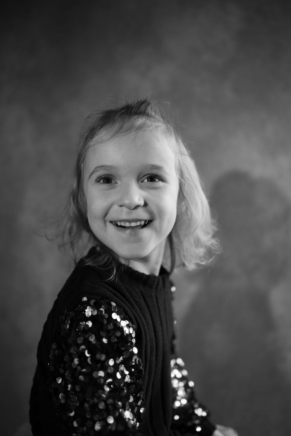 Black and white portrait series showing joyful expressions while wearing a sparkly dark top.