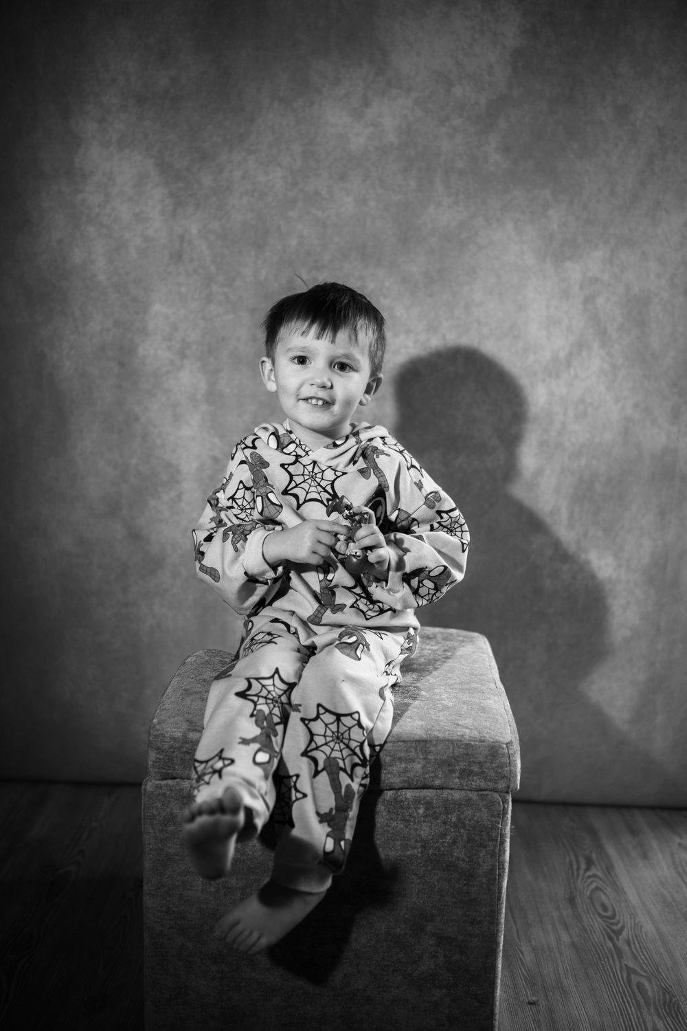 A sequence of black and white photos showing a small child in patterned pajamas playing and moving on a wooden floor.