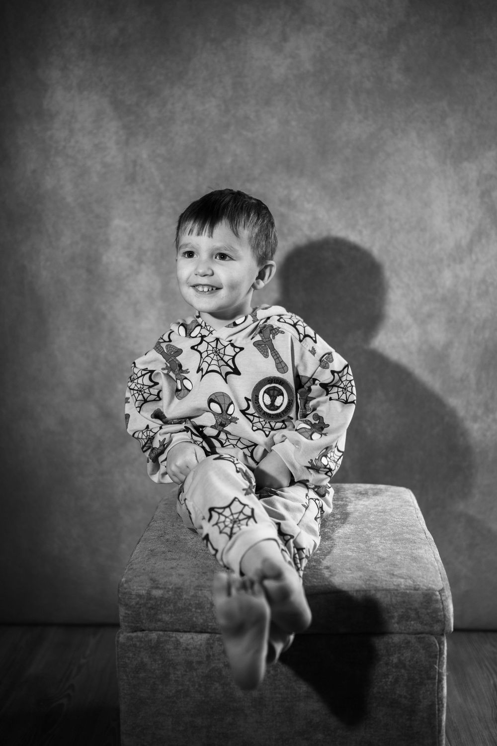 A child in patterned pajamas sits on a wooden bench in a series of black and white candid portrait photos.