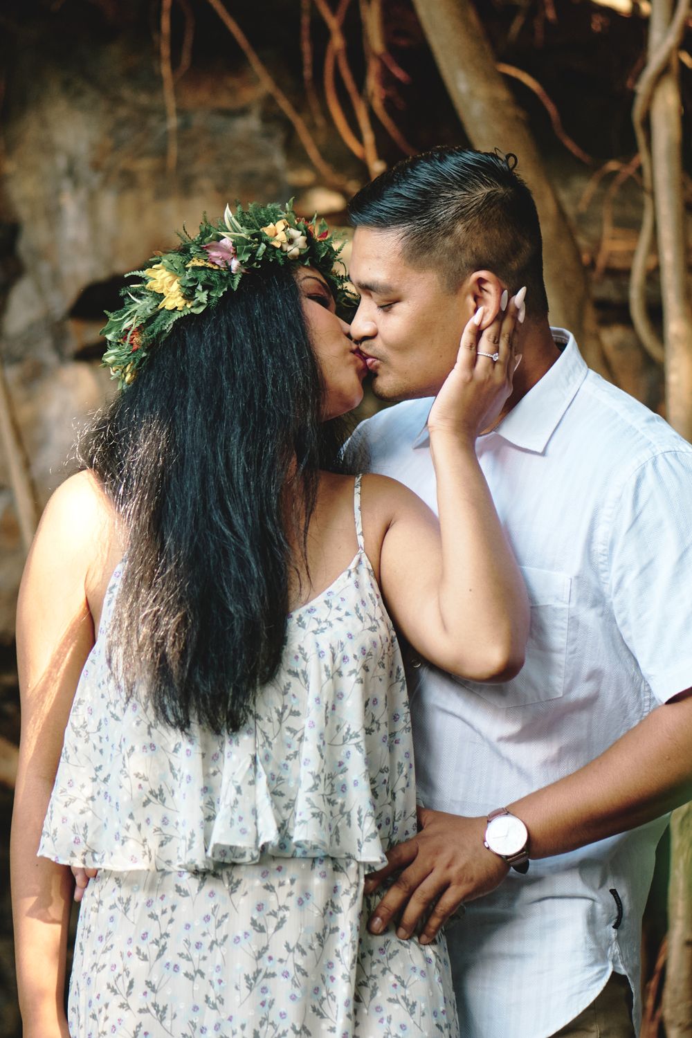 A couple shares an intimate moment among tropical foliage wearing floral crowns.
