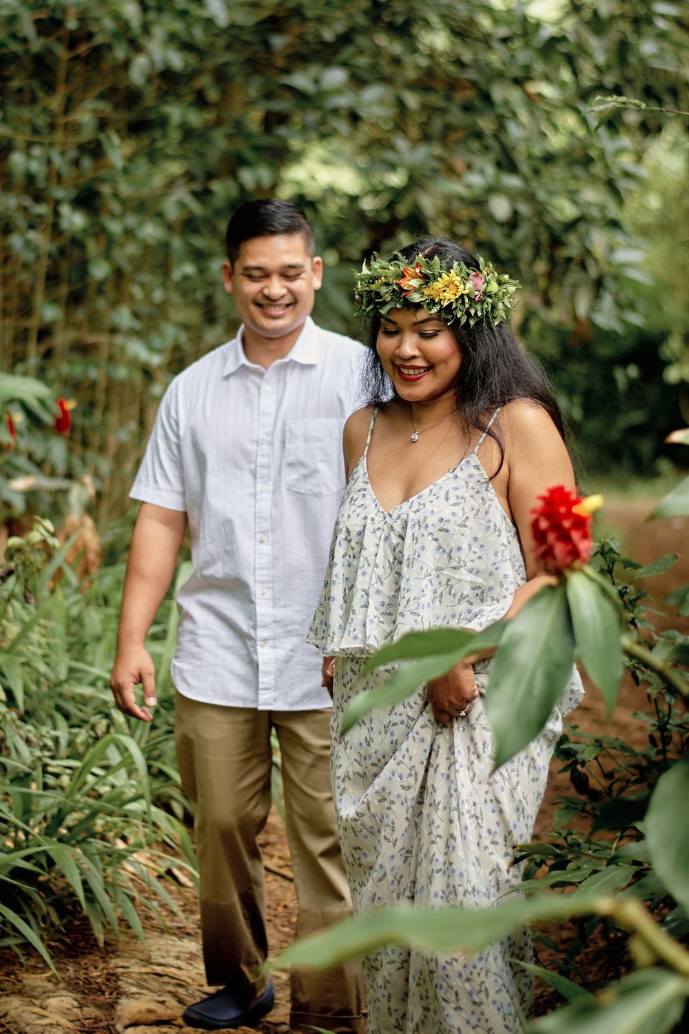 A couple walks through a lush garden path during their engagement photo session.