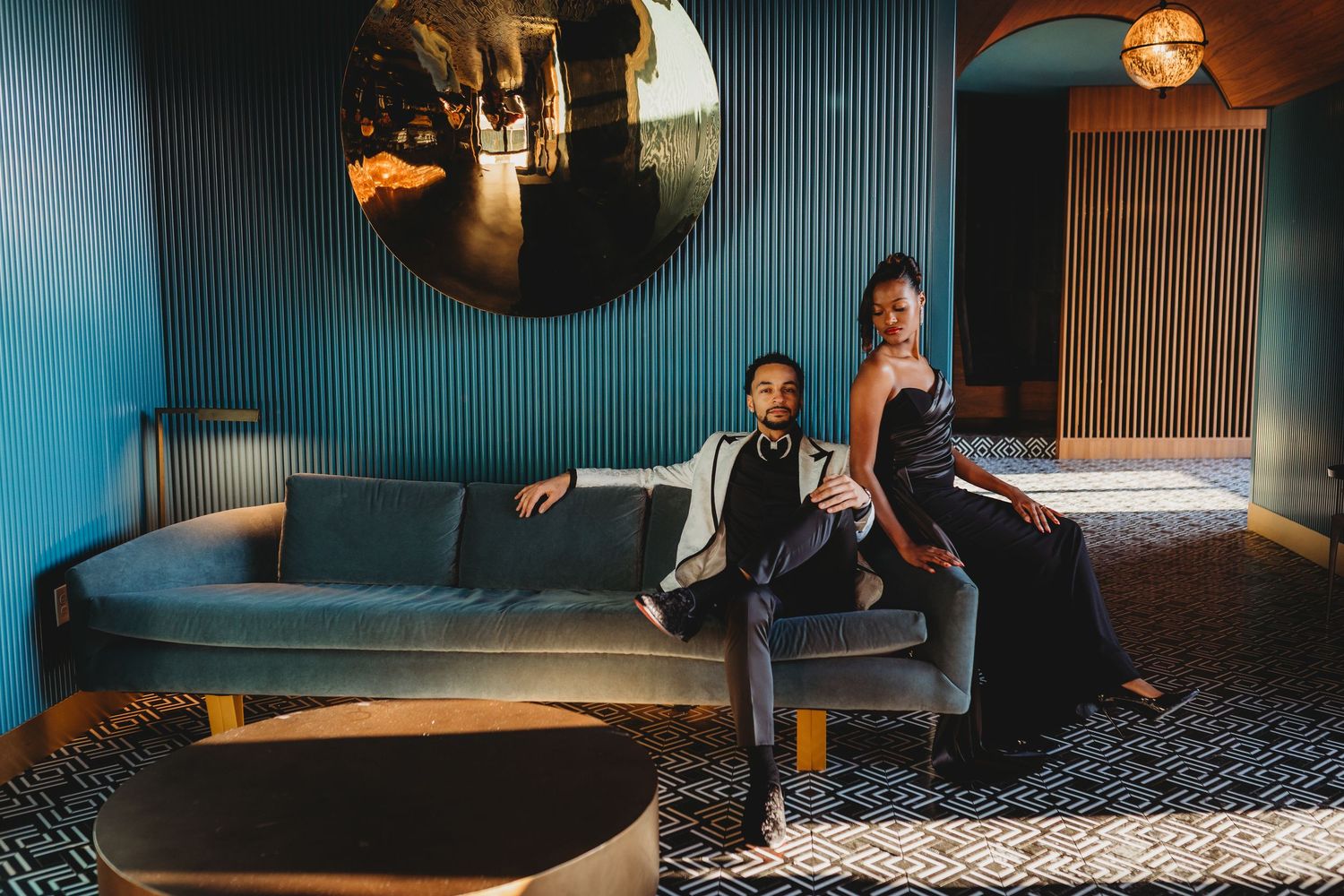 Modern hotel lounge interior with teal walls, geometric carpet, and warm accent lighting creates a sophisticated atmosphere.
