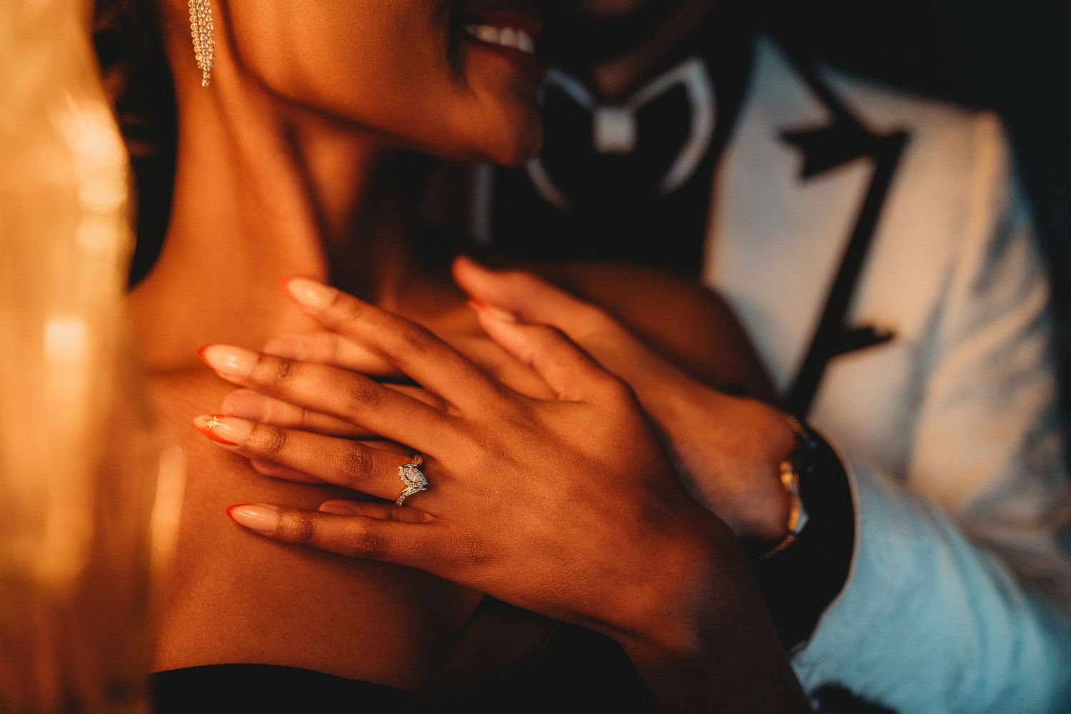 A couple embraces in warm lighting while wearing turquoise and white clothing during an intimate moment.