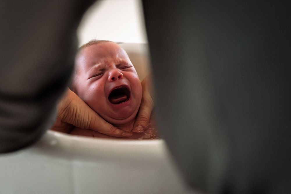 A series of six black and white photographs showing a baby's facial expressions during birth.