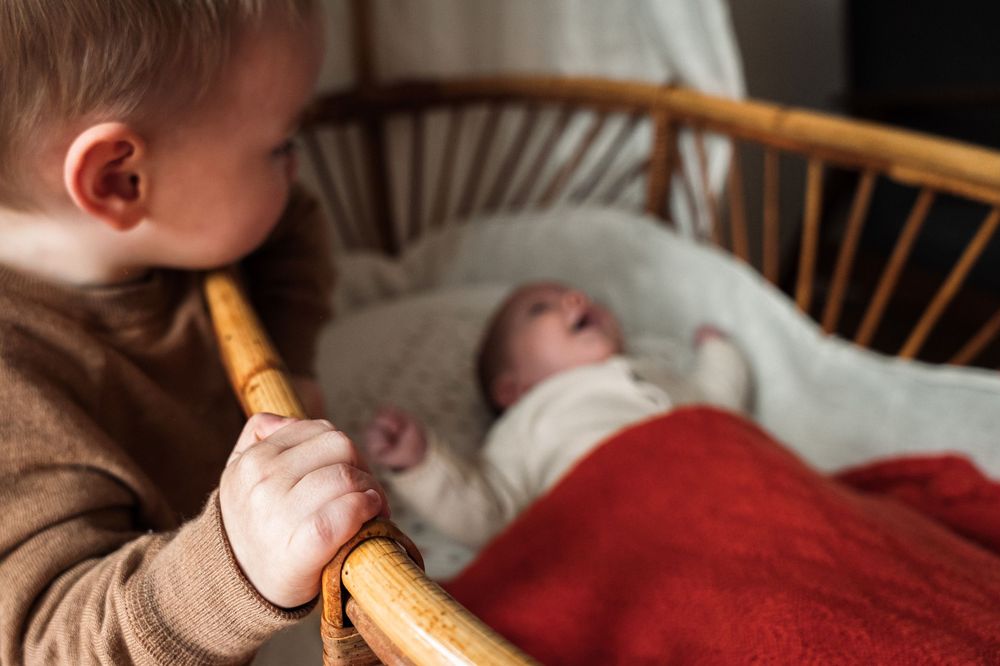 Baby sleeping in a wooden crib while holding a breadstick in their hand.