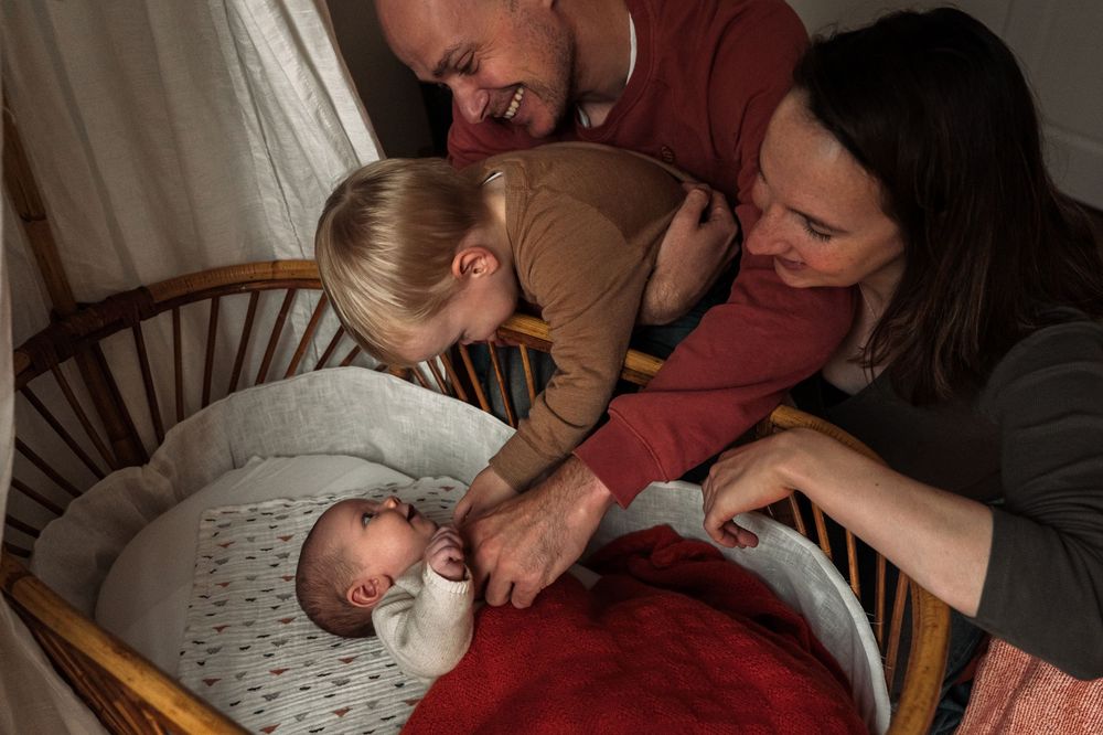 A series of photos showing a sleeping baby being comforted and held by parents in a dimly lit room.