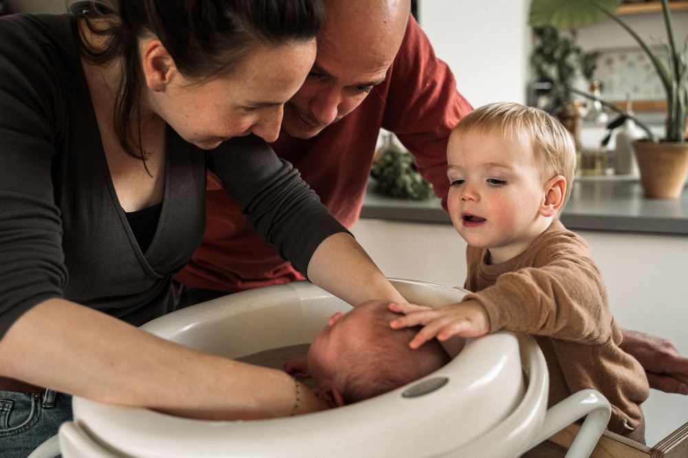A person comforting a crying child while sitting together on a white couch.