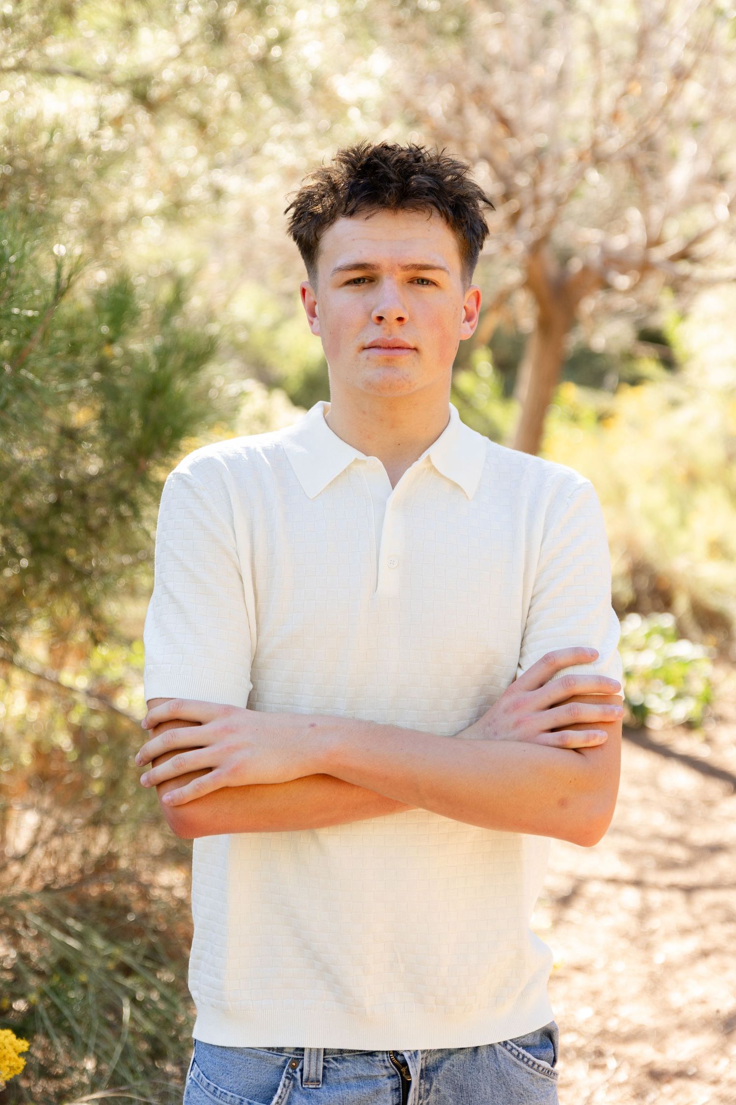 a senior boy in a white polo arms folded posing for the camera