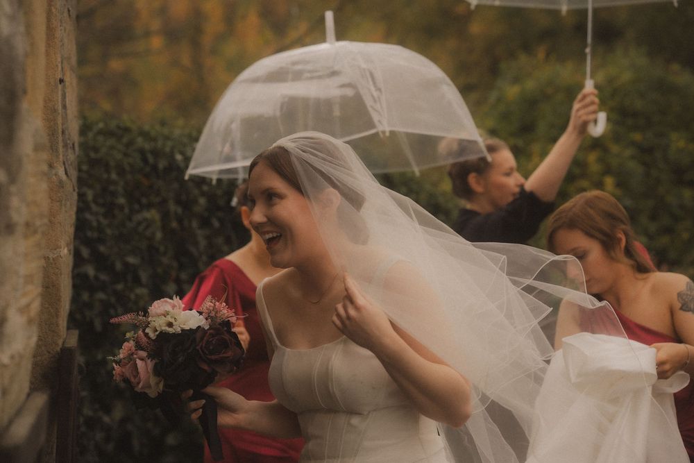 A joyful wedding party dances and celebrates together under a covered outdoor venue.