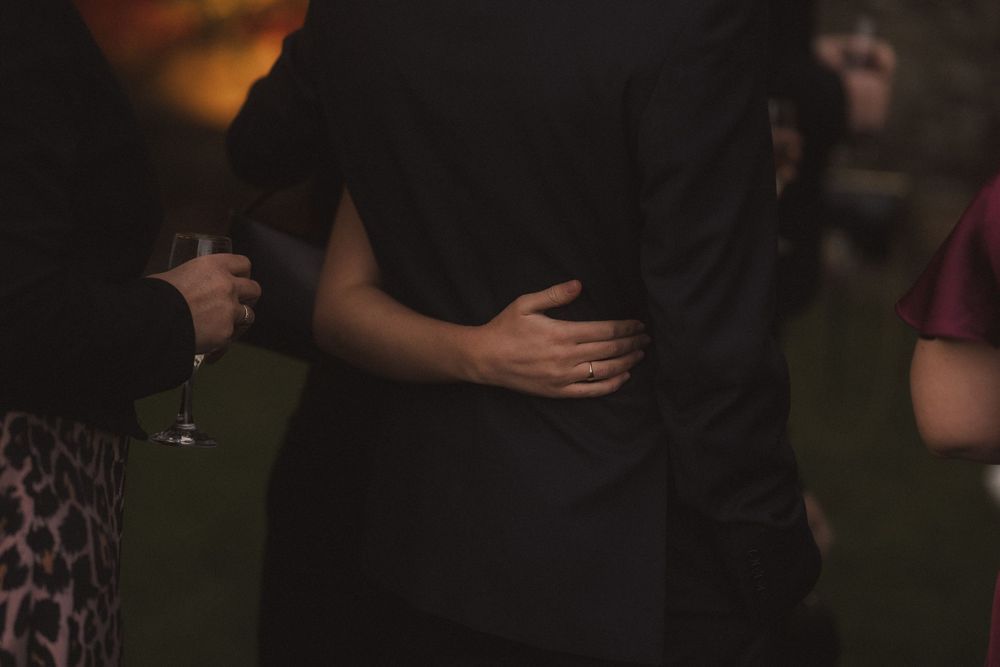 A group of people dance together at a party with warm lighting and dark ambiance in the background.