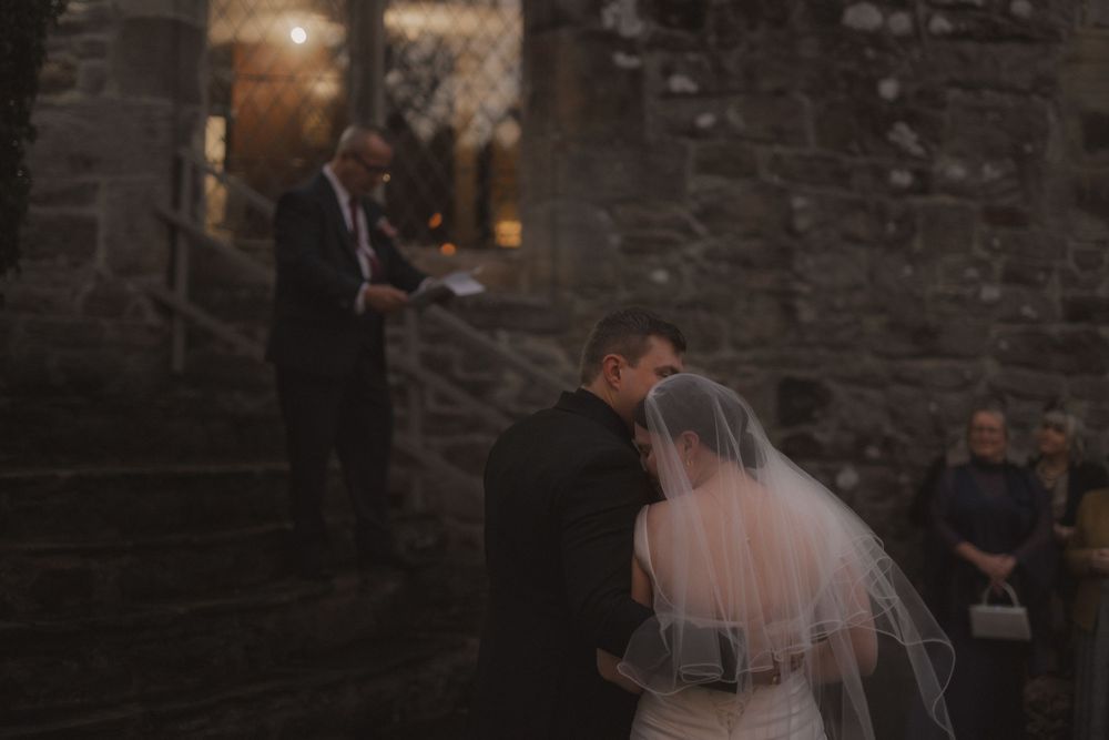 A bride and groom celebrate their first dance together at a rustic brick-walled wedding reception venue.