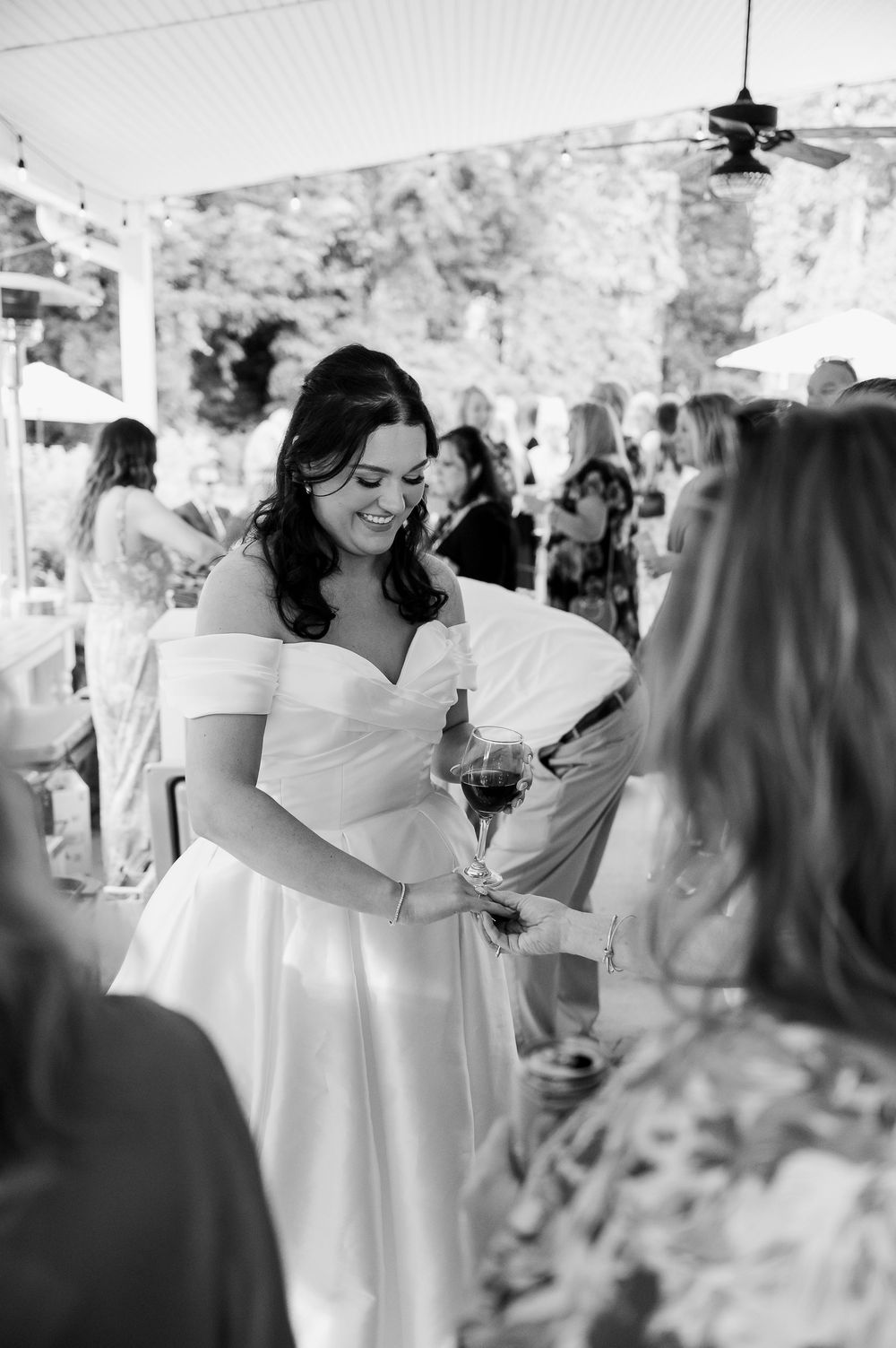 A candid moment at a wedding reception as guests mingle under a covered porch area.