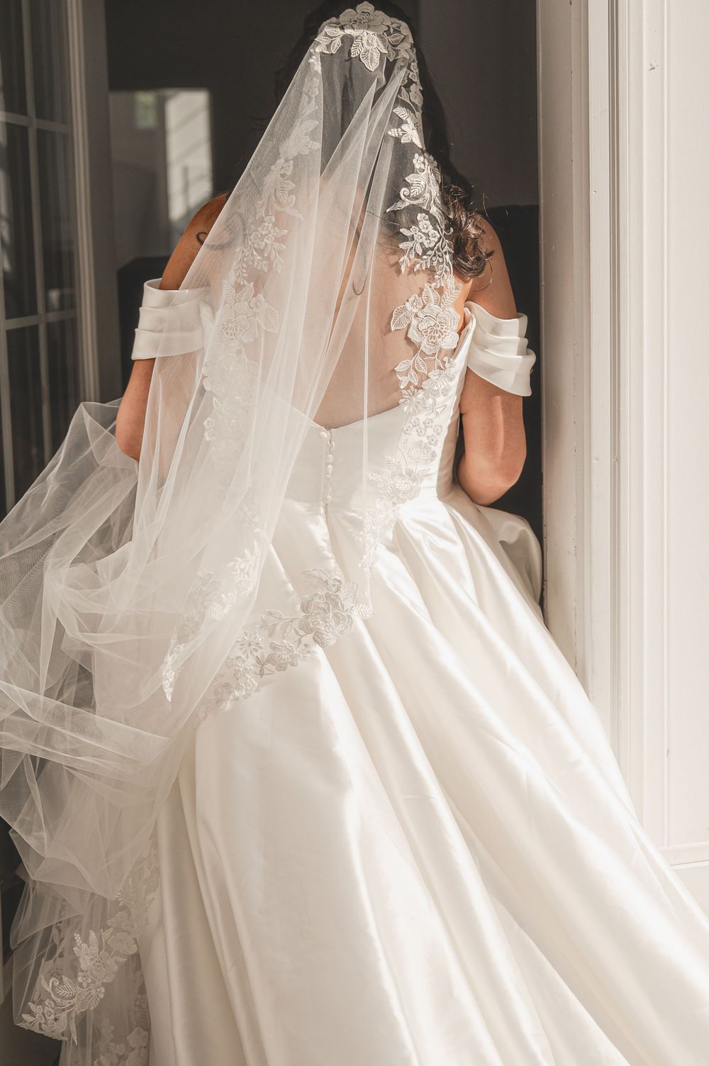 Elegant white wedding gowns with flowing veils captured in soft natural light.