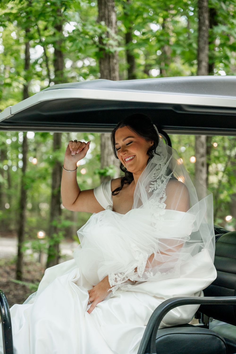 Wedding party laughing together in a golf cart decorated with white tulle.