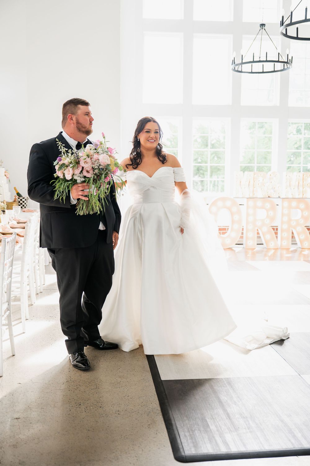 Wedding couple sharing intimate moment in bright white reception venue.