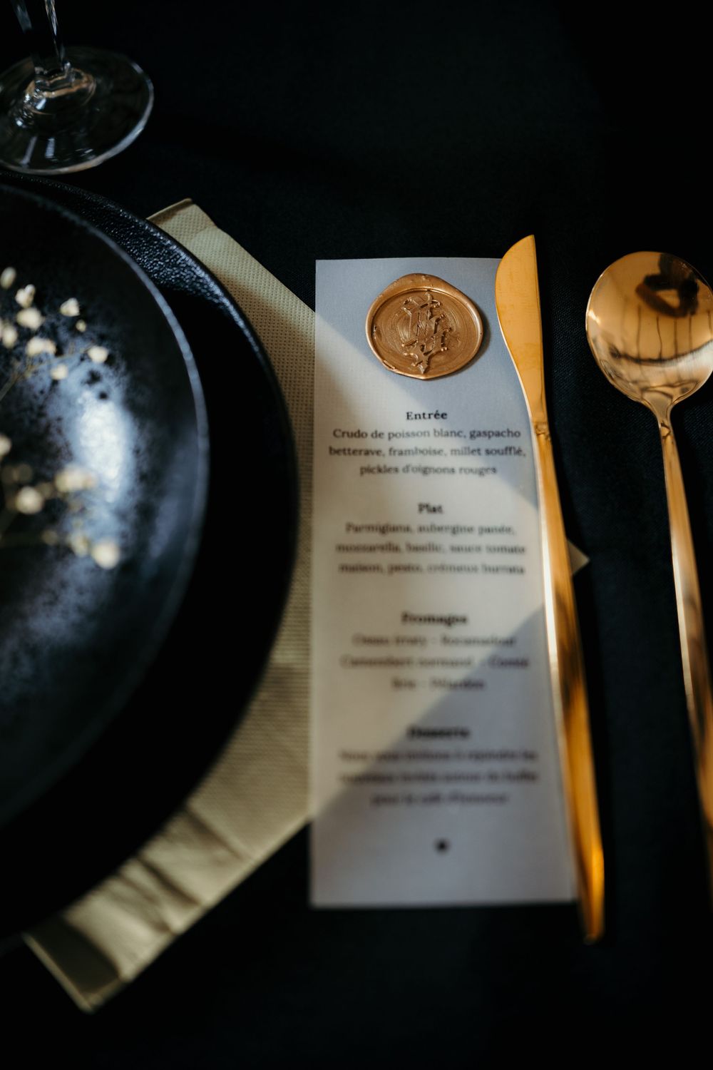 A restaurant menu and black plate are artistically photographed in moody lighting with selective focus.