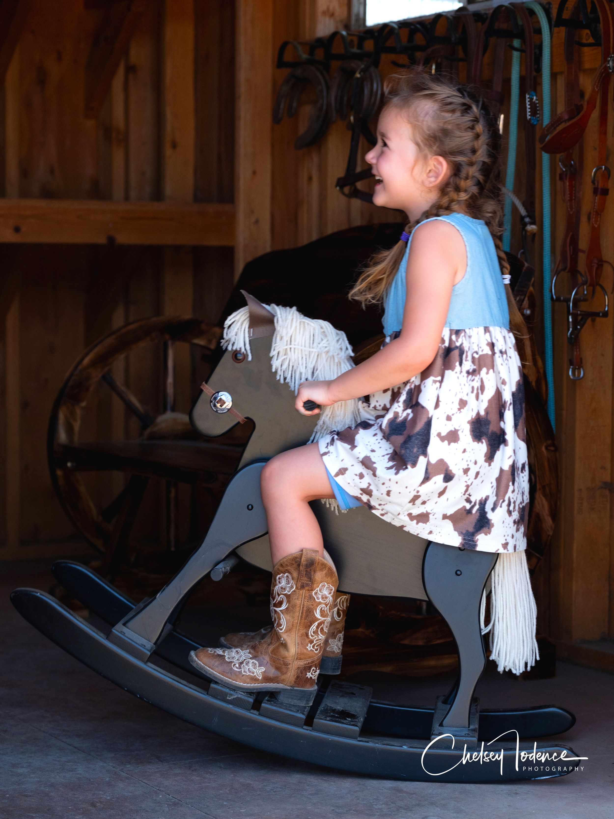 Young child riding a rocking horse in a rustic tack room, capturing a warm and playful moment during a children's photo session in Petaluma
