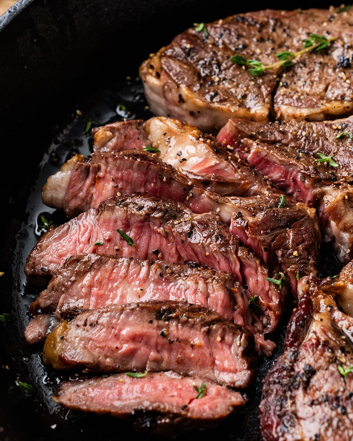 Meat in cast-iron pan sprayed with olive oil to make it shine for food photos.