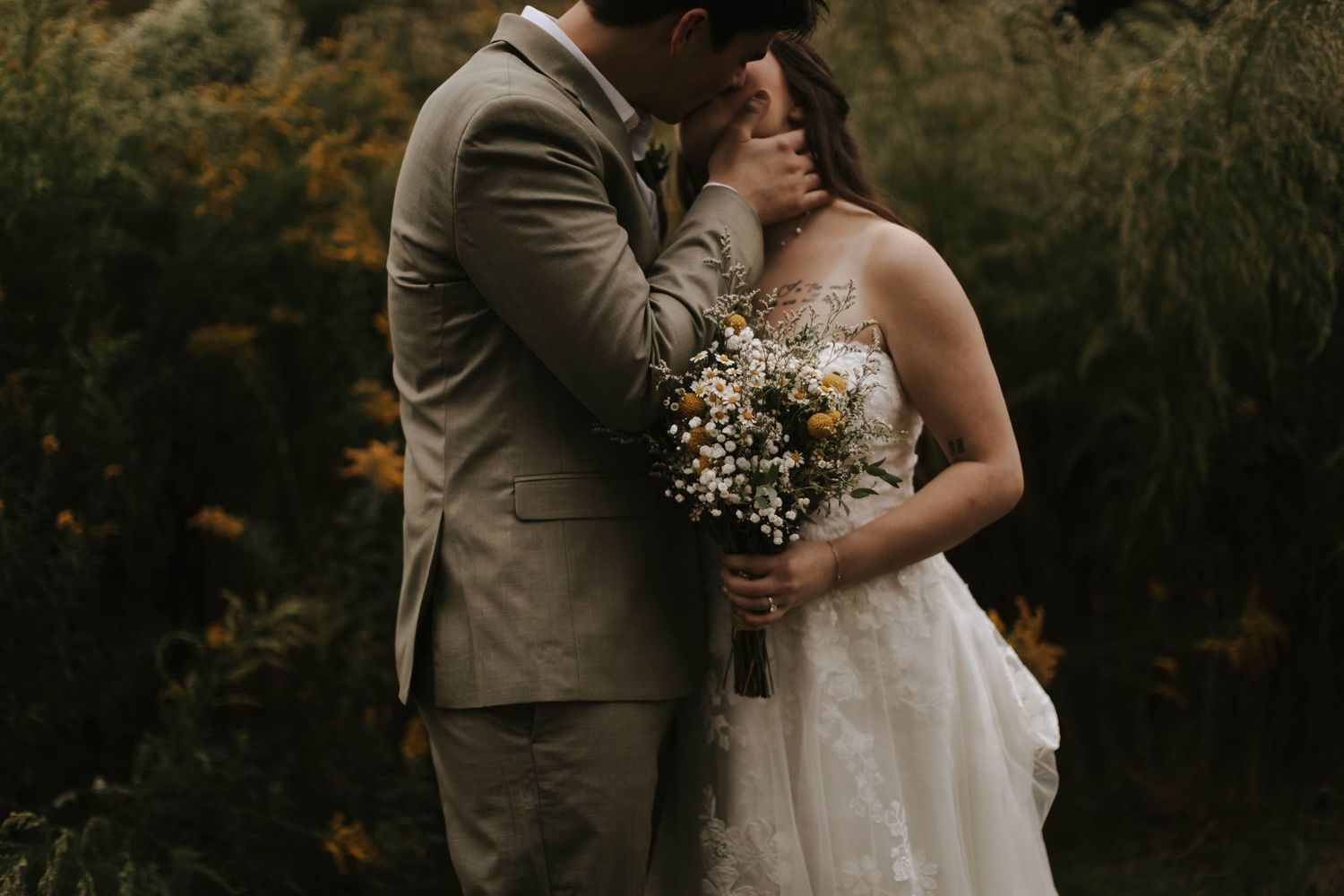 Couple embracing in an outdoor setting with natural foliage and golden light.