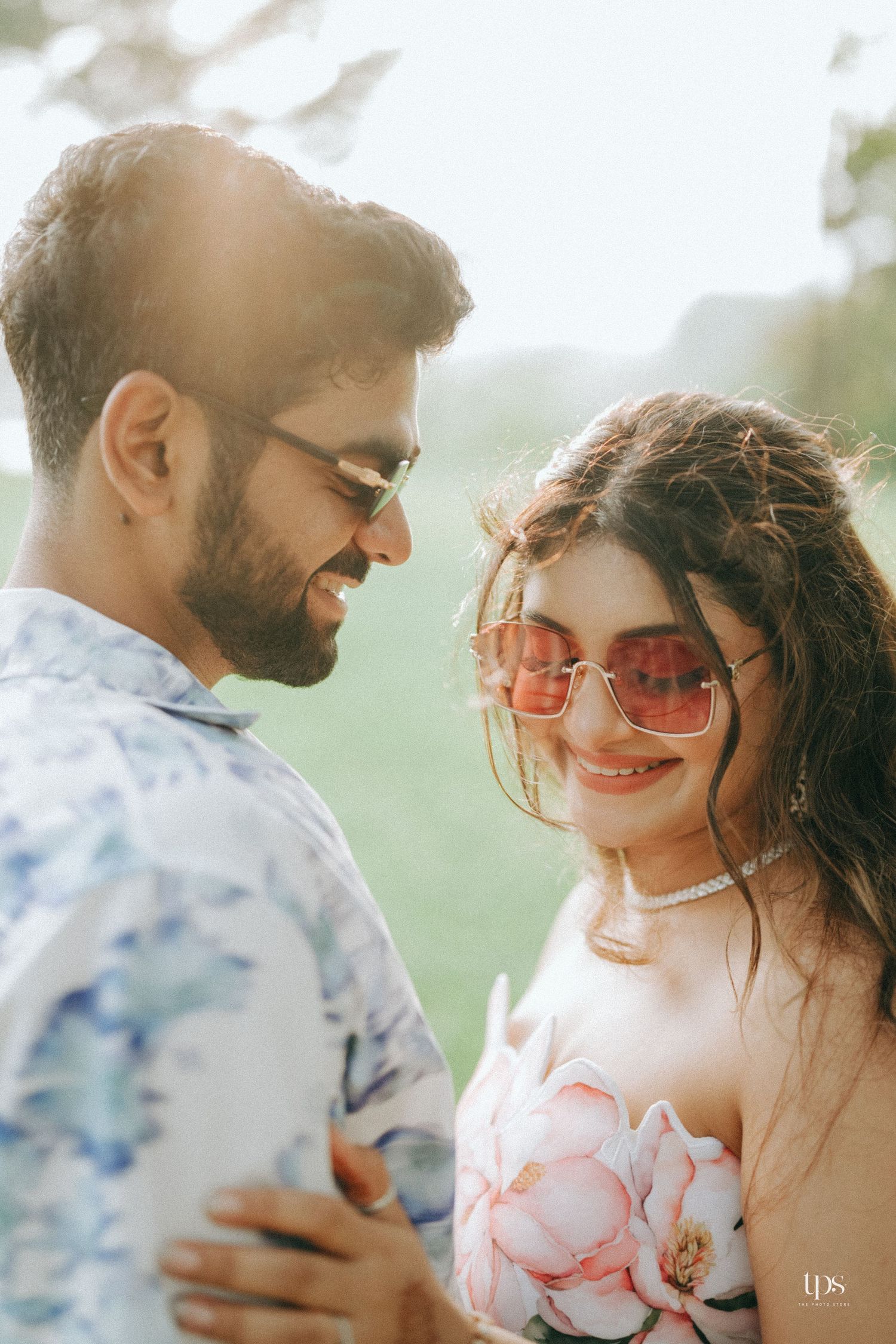 A romantic couple shares an intimate moment outdoors while wearing sunglasses.