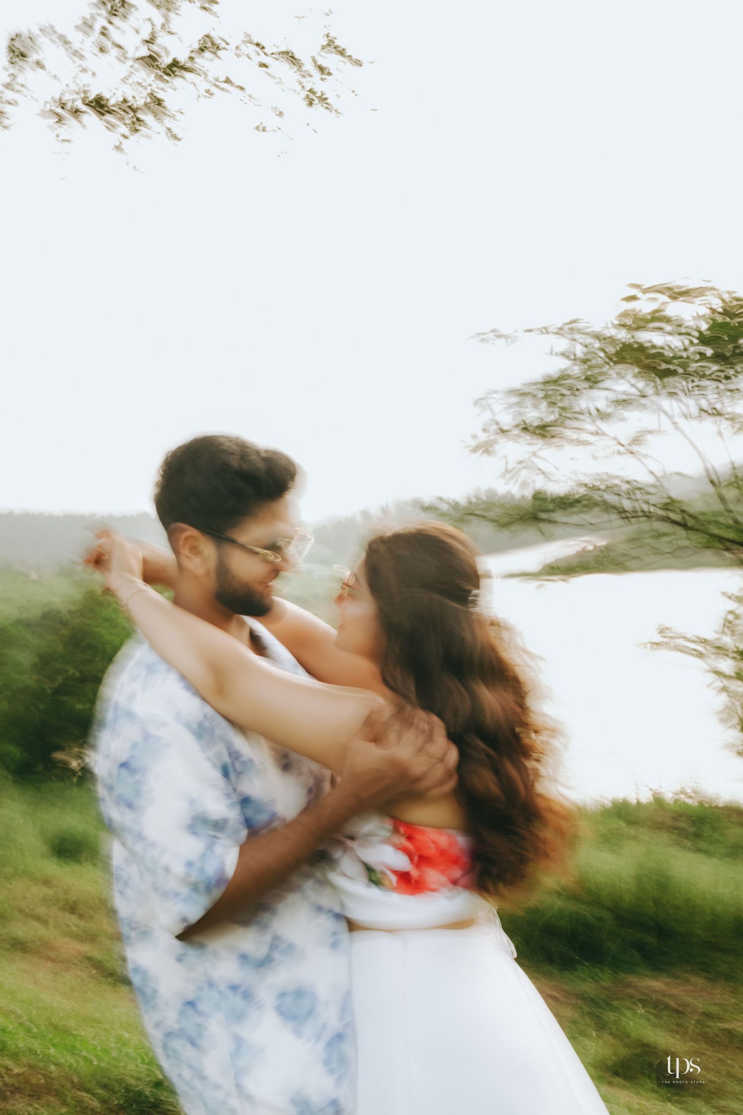 A couple spins together in a romantic dance pose against a natural landscape.