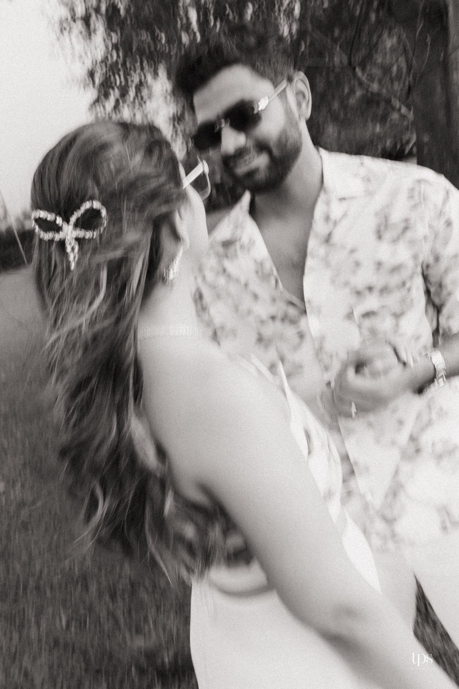 A black and white photo of a couple dancing and laughing together outdoors.