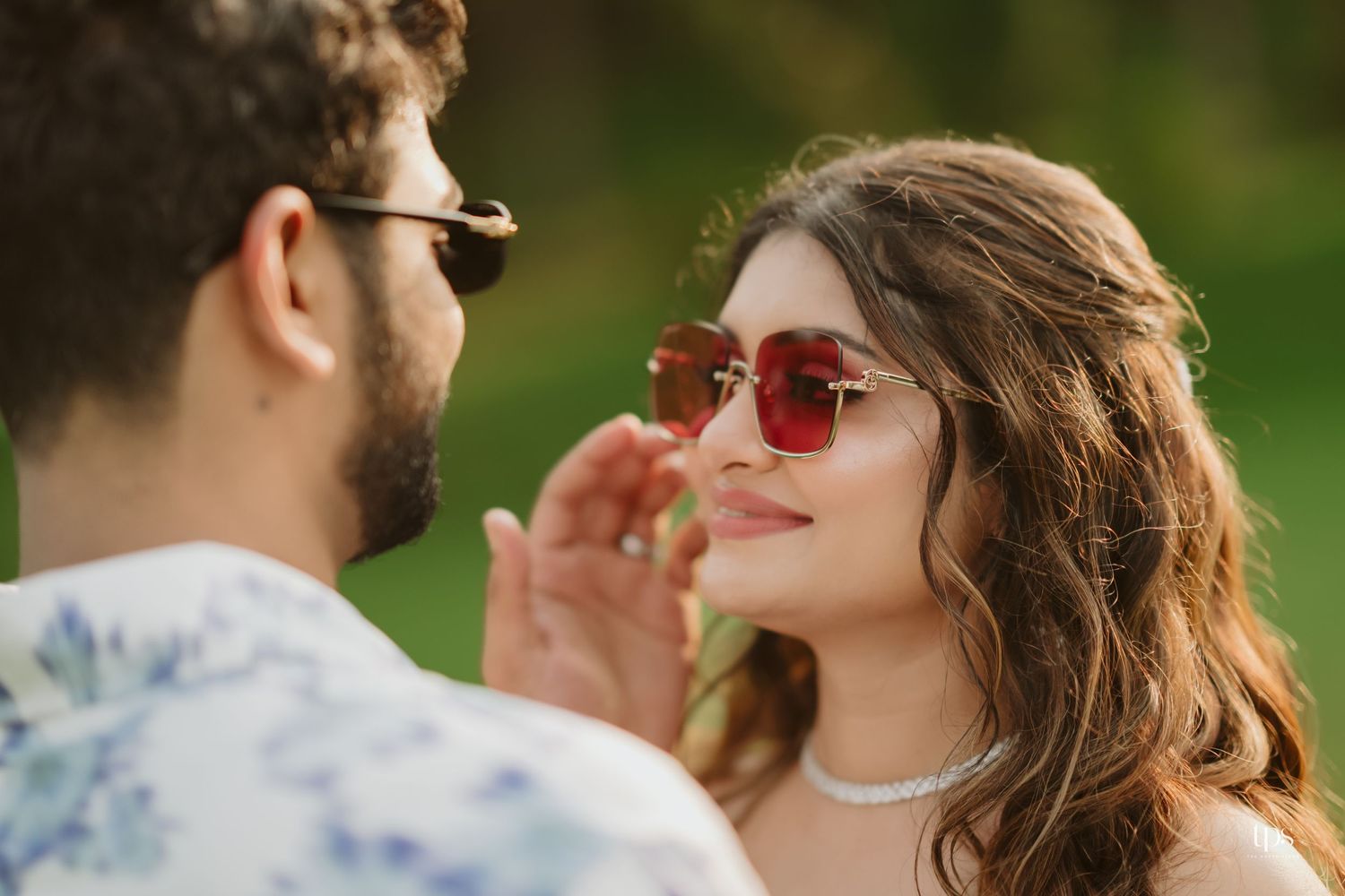 A tender moment captured between a couple wearing sunglasses during an outdoor photoshoot.