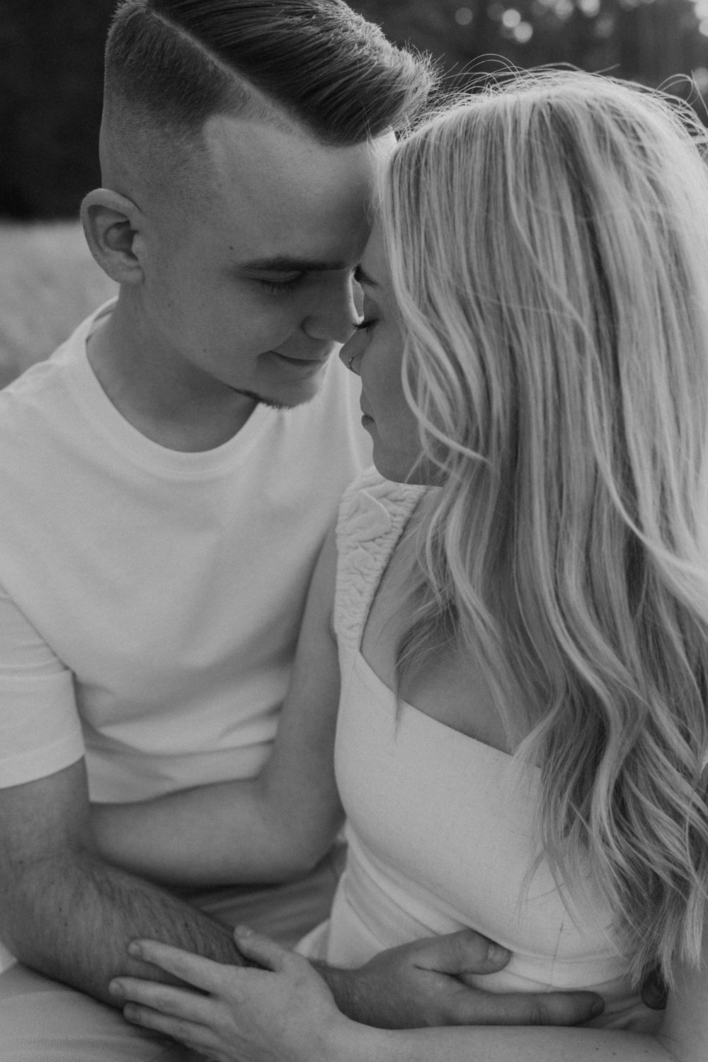 An intimate black and white portrait of a couple sharing a close moment.