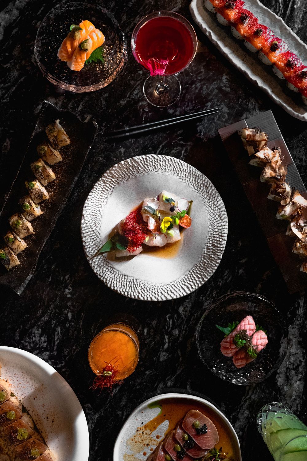 Overhead view of elegant dinner spread with various dishes and cocktails on dark marble table. Mtlshutter photography