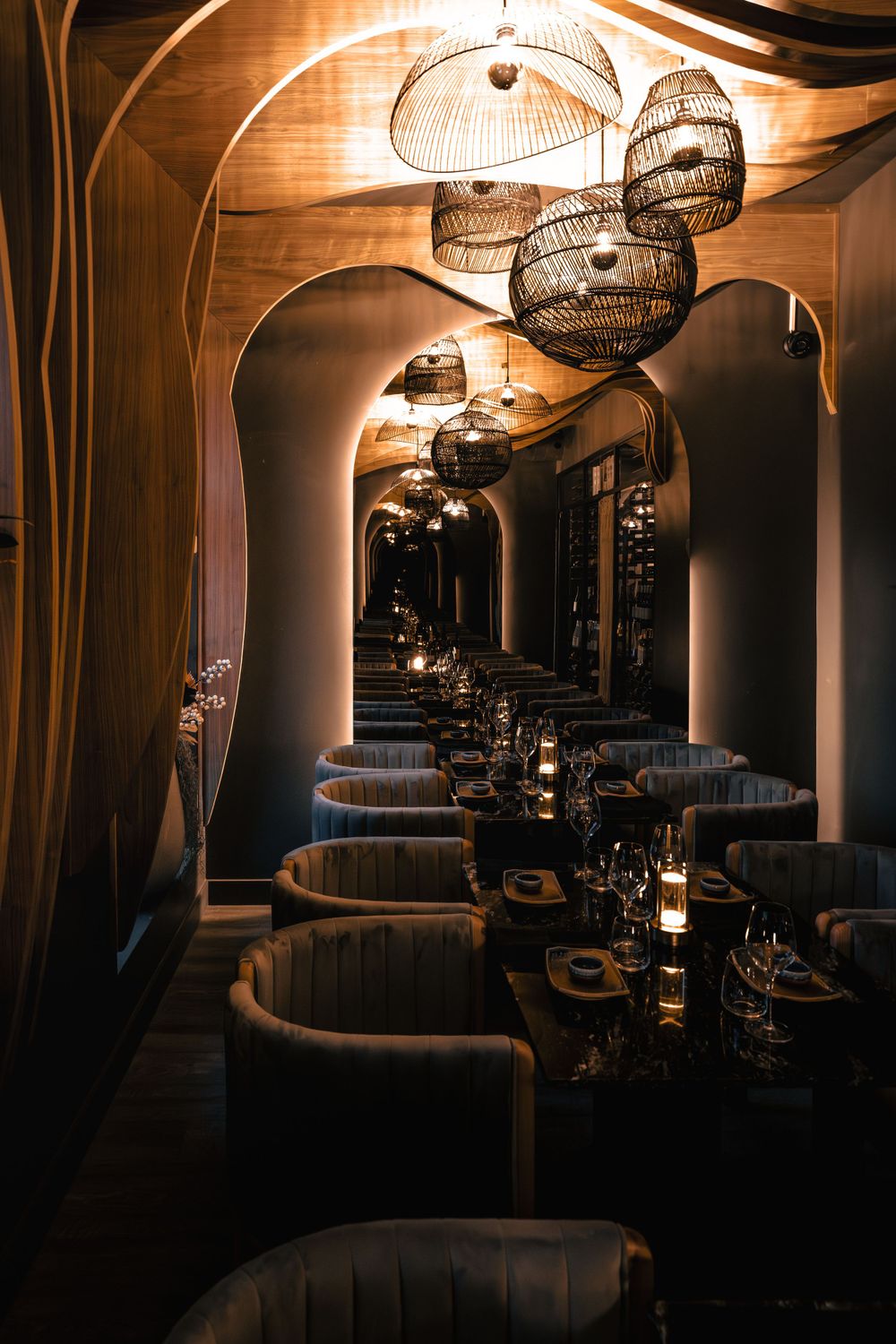 Elegant restaurant interior with arched hallway and hanging woven pendant lights creating warm, moody ambiance. Mtlshutter photography