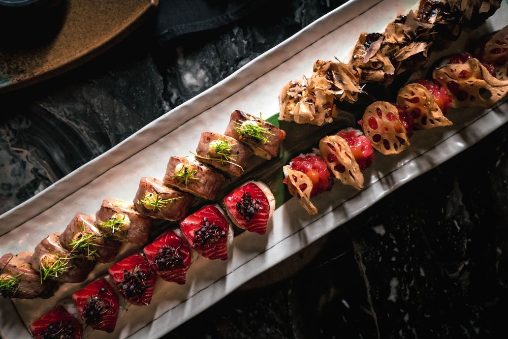 Colorful array of specialty sushi rolls arranged on white rectangular plate with garnishes. Mtlshutter photography