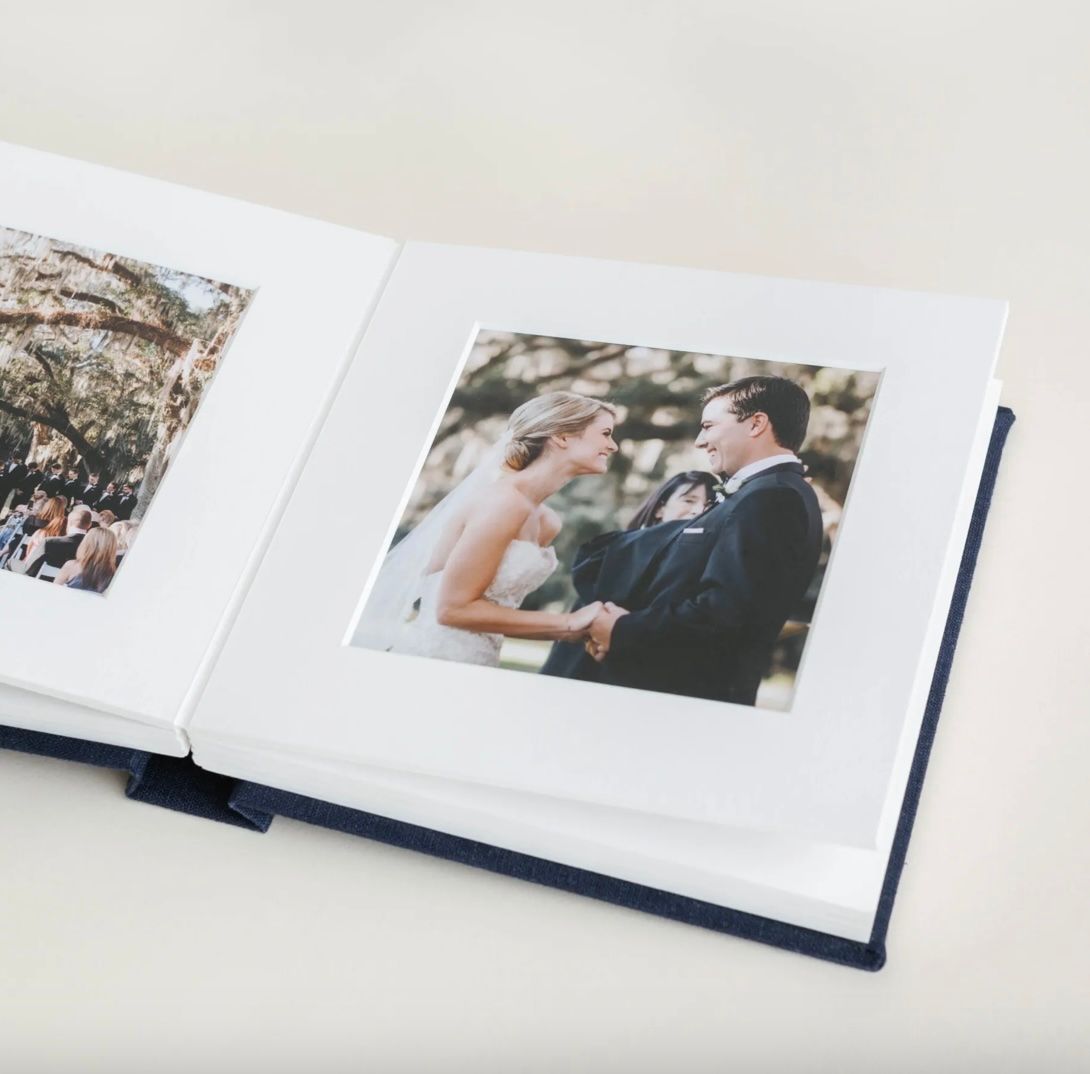 Wedding photo album showing a ceremony moment displayed in an elegant white matted book.