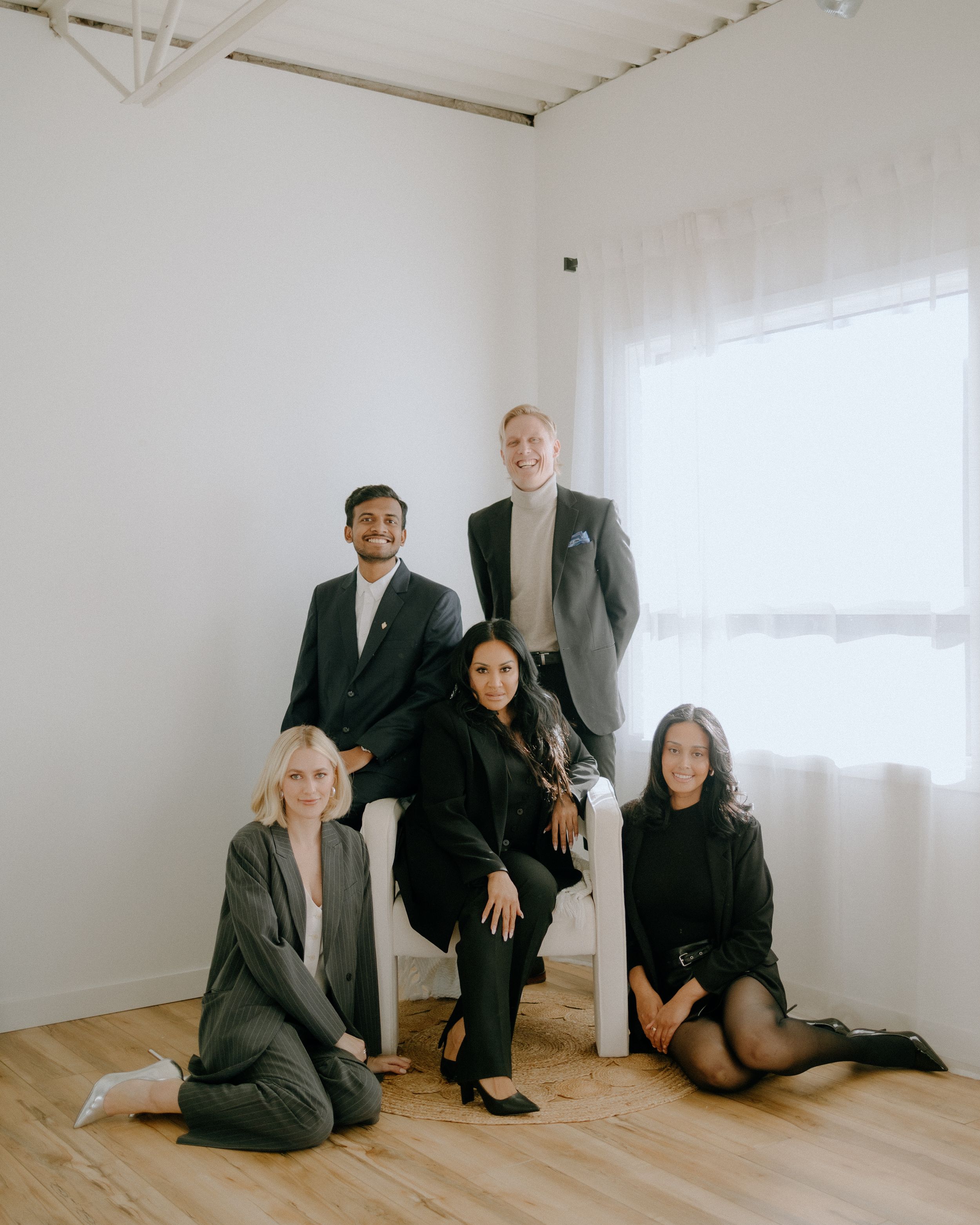 A professional business team poses together in a minimalist white room.