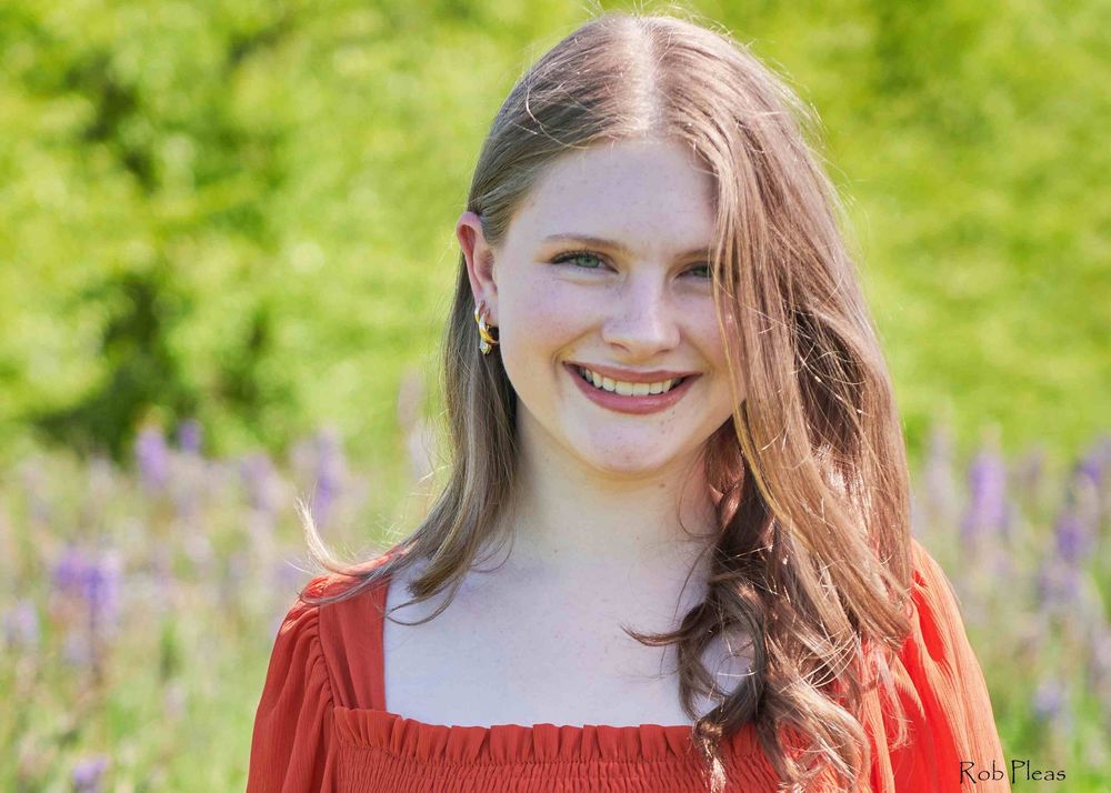 High school senior female wearing orange dress in Lupine fields near Farm 12 in Puyallup, WA