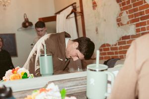 Someone leaning over a table with mint-colored drinks and orange floral decorations at a rustic event space.