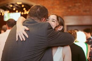 Romantic couple dancing close together at rustic brick-walled wedding reception venue with warm lighting.
