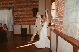 Two people dancing and celebrating in front of exposed brick walls at an indoor venue.