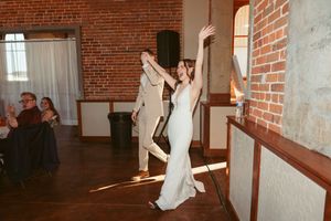 Couple celebrates dancing together in a rustic brick-walled wedding venue.