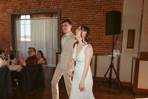 A couple shares their first dance in an industrial-style venue with exposed brick walls and romantic lighting.