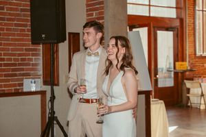 Couple stands together during wedding reception in industrial brick venue.
