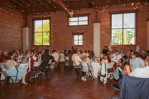 Wide view of a wedding reception in a rustic brick venue with natural light streaming through windows.
