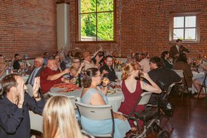 People gathered in a rustic brick venue for what appears to be a wedding reception or celebration event.
