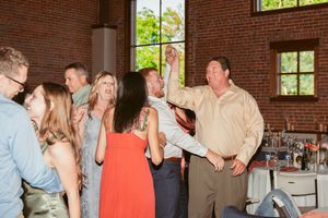 Group of people celebrating and dancing at an indoor event in a rustic brick-walled venue.