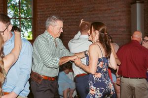 Guests dancing together at wedding reception in rustic brick venue.
