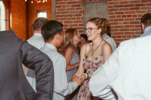 Candid moment at a party showing people chatting and laughing together in front of exposed brick wall during evening event.