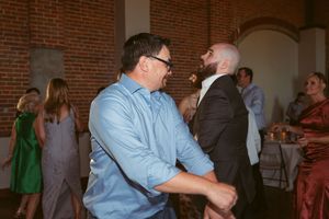 People dancing together at a social gathering in a rustic brick-walled venue during a celebration event.