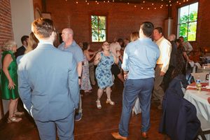 Wedding guests dancing on a wooden floor in a room with exposed brick walls and large windows.